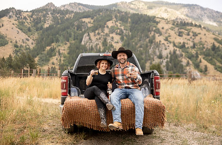 Joe and Jennifer sitting on a Truck Cheersing in Jackson Hole