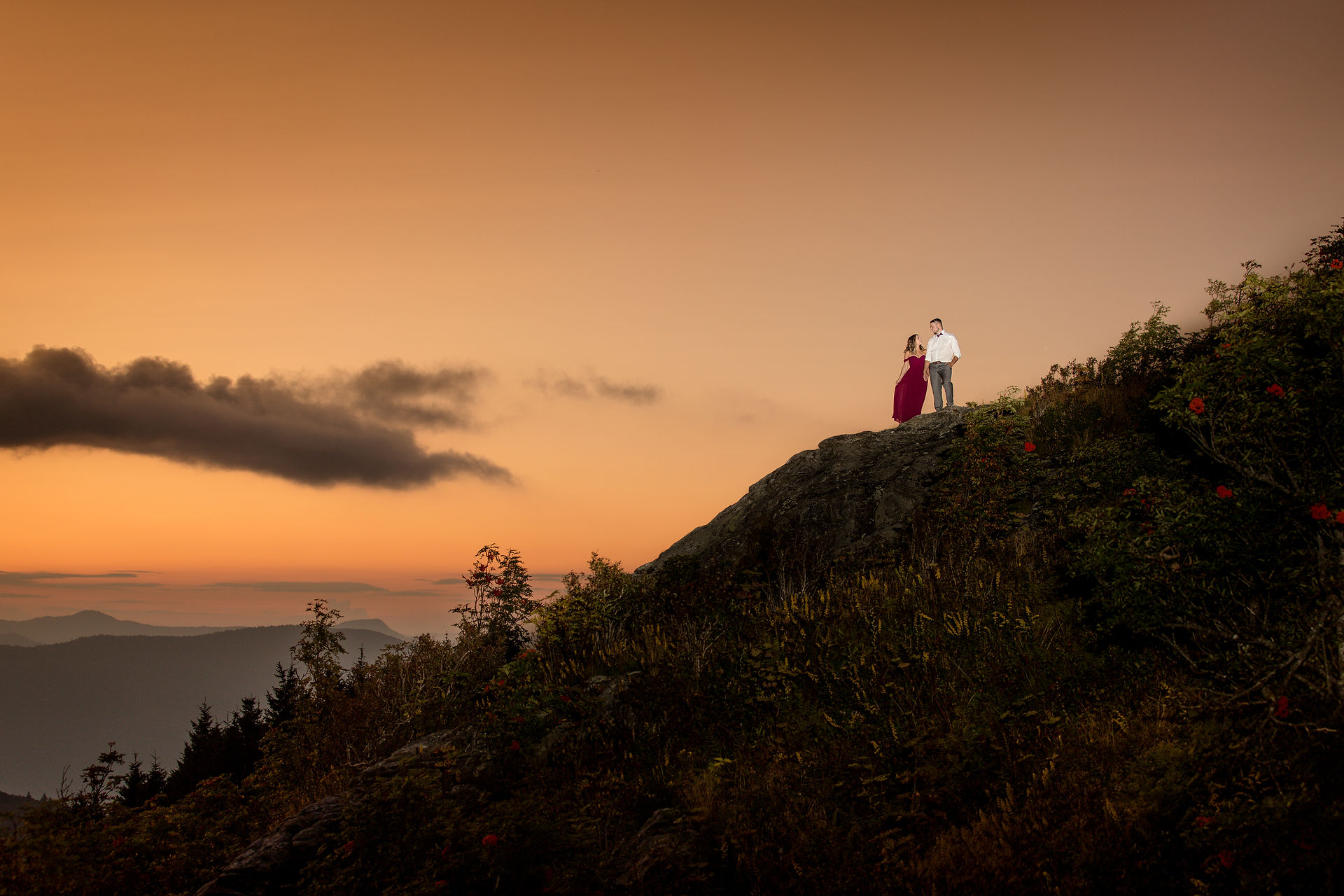 engaged couple standing on the edge of a cliff 