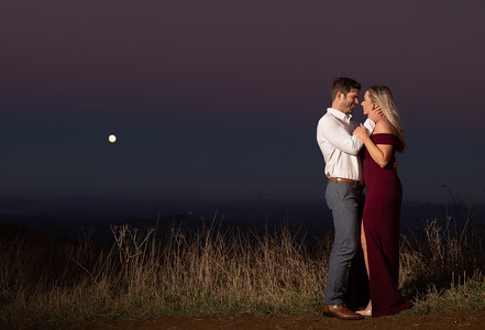 man caressing his fiance in front of the moon 