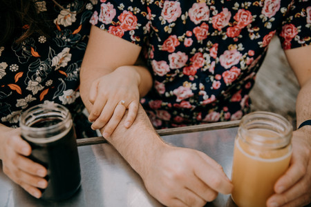 A couples hands holding beers. 