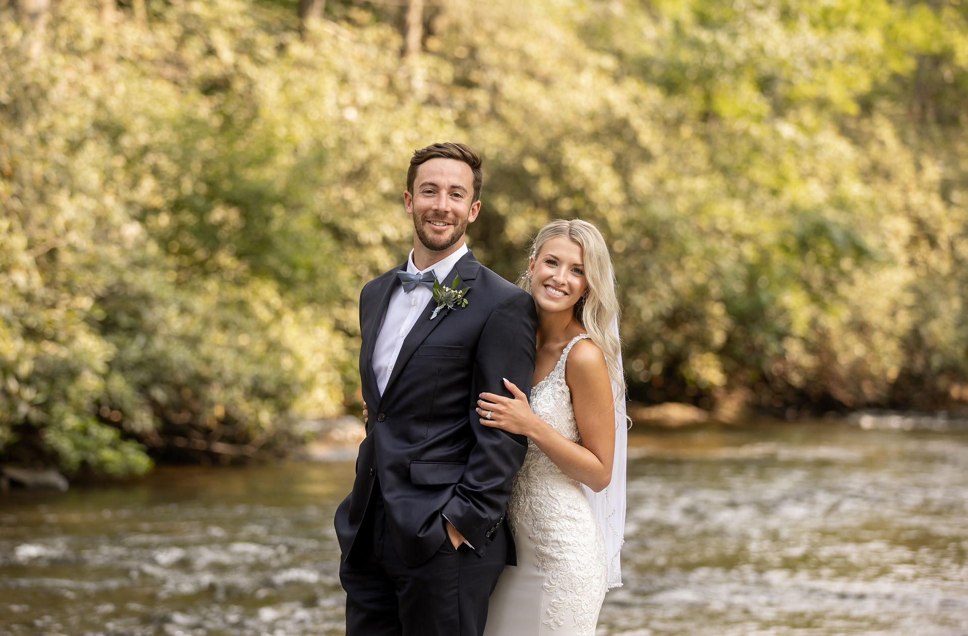 bride and groom smiling as bride holds groom from behind 