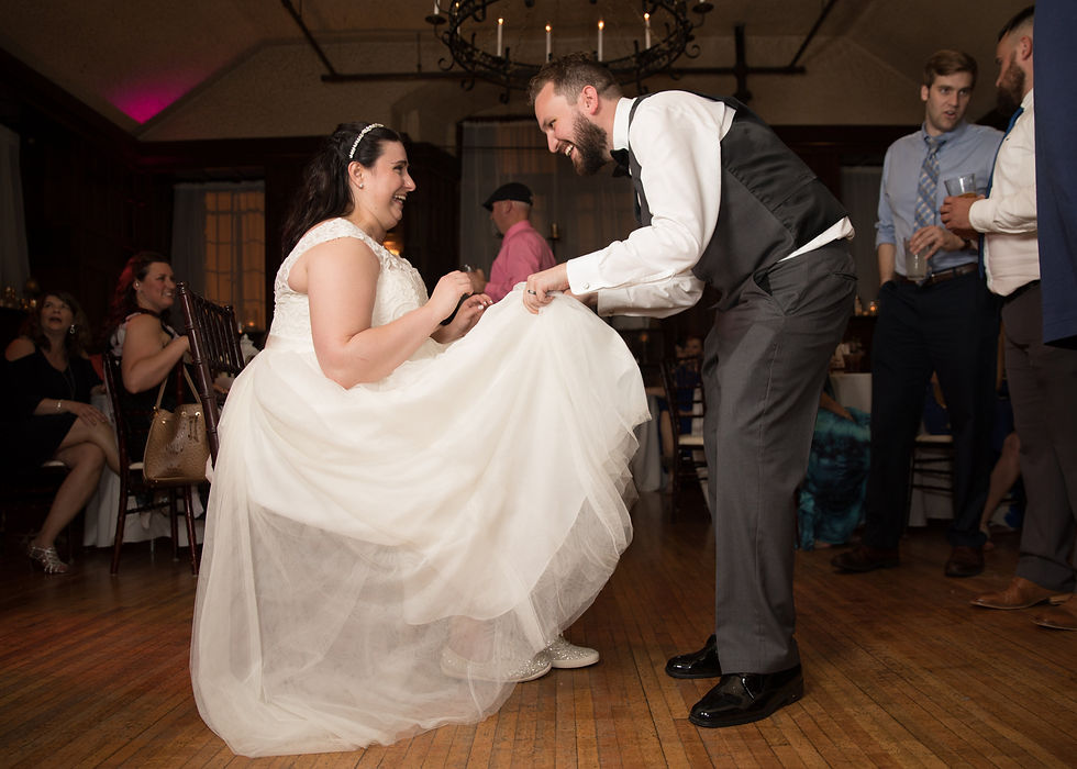 bride laughing while the groom goes to get the garter
