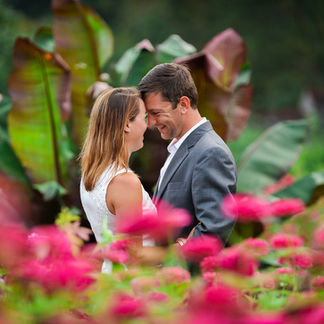 couple touching foreheads in behind some flowers