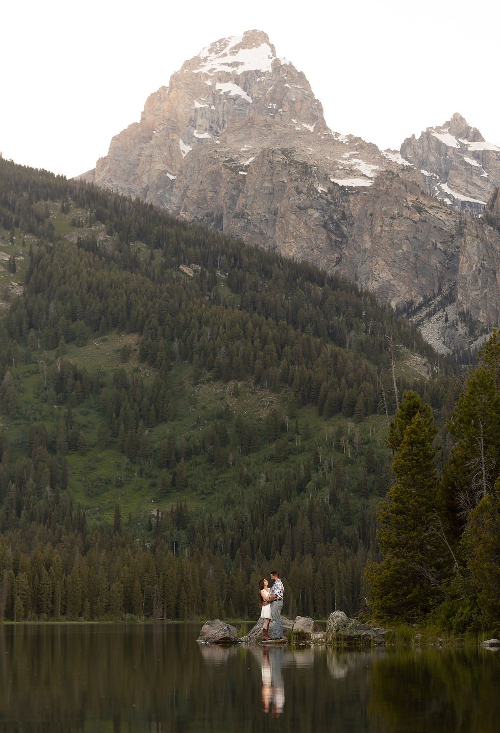 a couple holding each other close in front of a large mountain