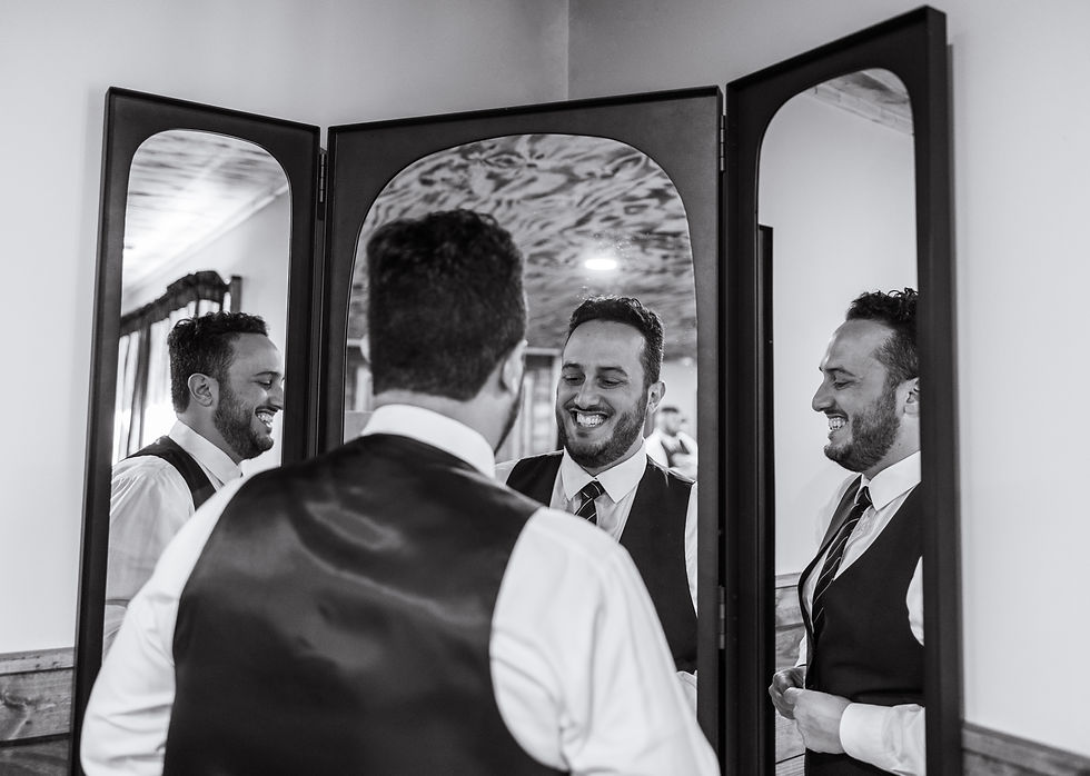 grooms smiling in the mirror as he gets ready