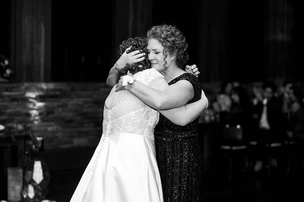 The bride's mother hugging her closely.
