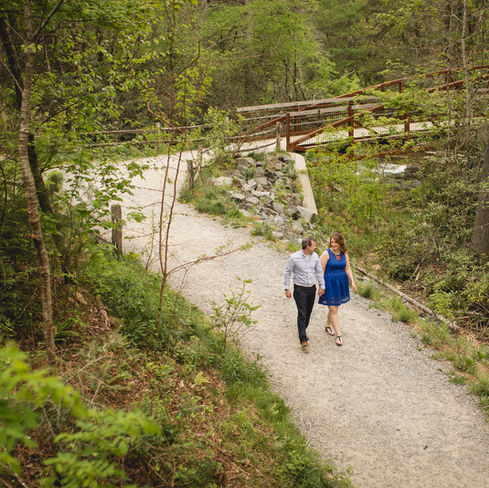couple holding hands and walking down a path