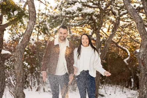 A couple laughs as the snow falls in front of them.