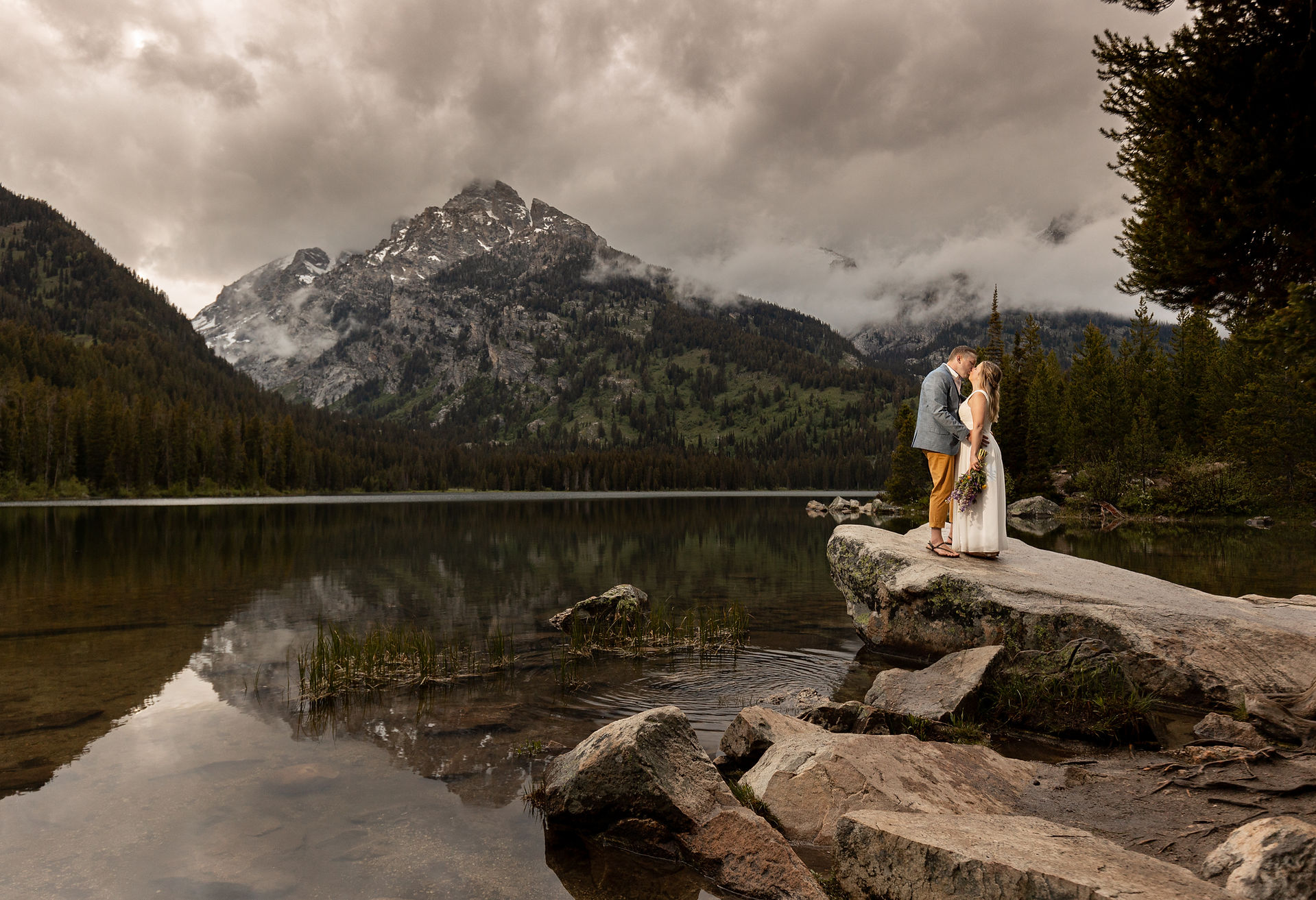 A dramatic sunset kiss between a bride and groom at taggart lake.