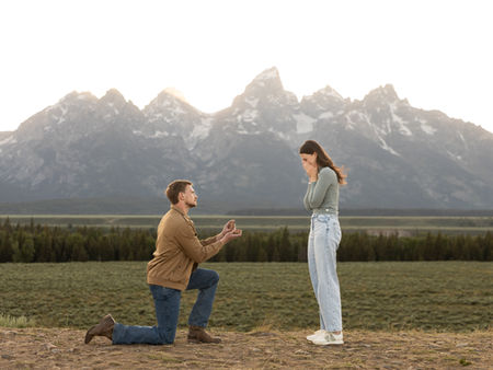 A man proposing to his girlfriend in front of the grand tetons.