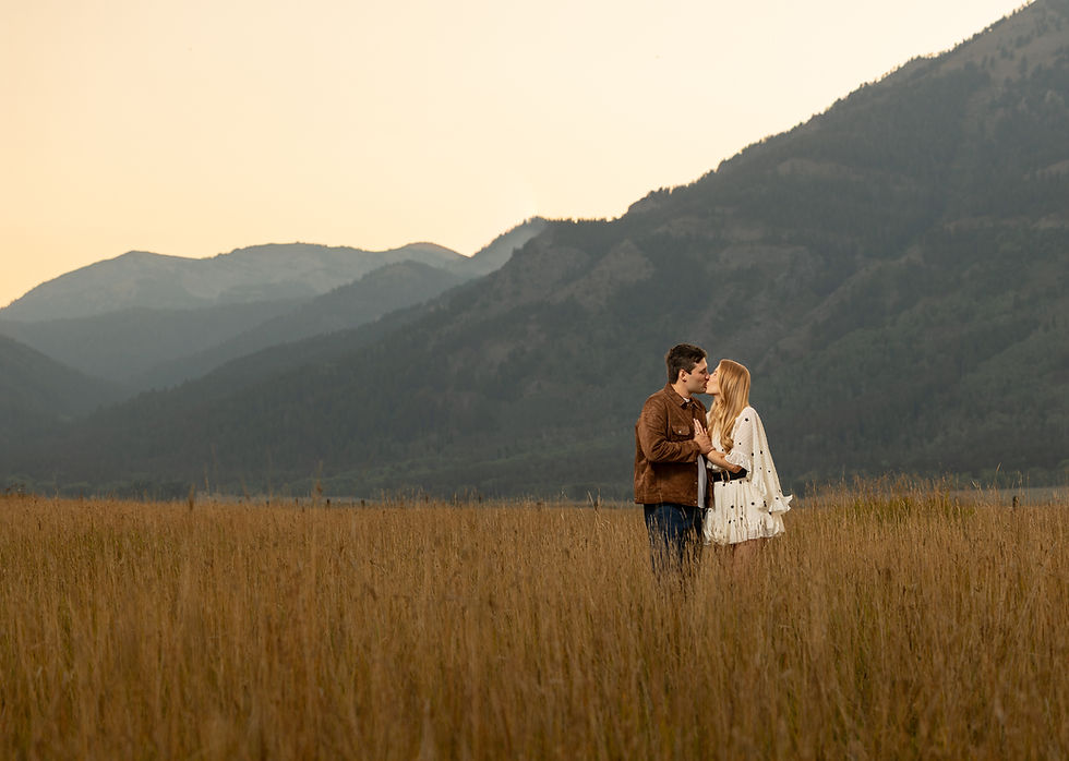 A dramatic lighting portrait of a couple kissing in a tall grassy field at Tammah Jackson Hole.
