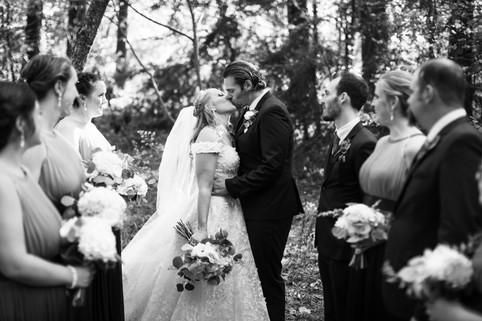 bride and groom kissing in between the bridal party members