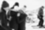 A woman hugs her family members moments after her surprise proposal. A skier skis by in the background and looks on at the celebratory moment.
