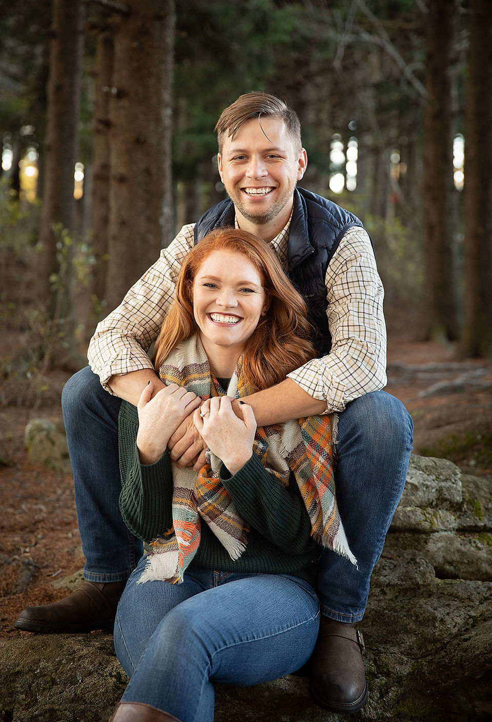 woman sitting between her fiance's legs as he hugs her 