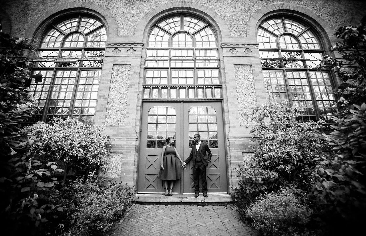 couple holding hands in front of a grand door at the biltmore 