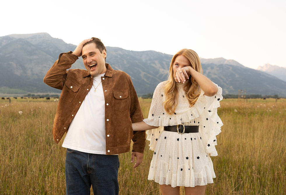 A man laughing and pushing his hair back as his fiance wipes away tears.