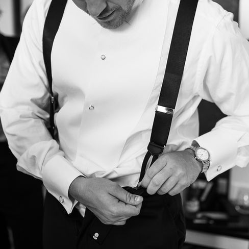 groom putting his suspenders on