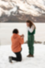 a woman covering her face as her boyfriend proposes
