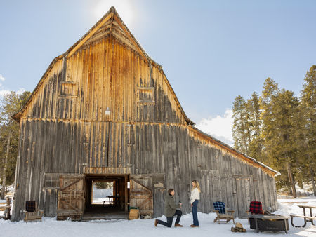 A man proposing to his girlfriend in front of an old rustic barn at Snake River Ranch.