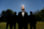 silhouette of the groomsmen while the groom is spot lit 