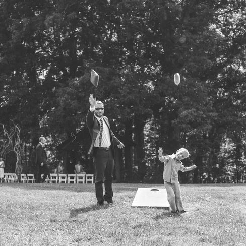 little boy and his dad playing corn hole