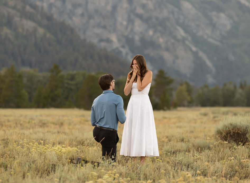 A woman covers her face in shock moments after her boyfriend drops to a knee to propose.