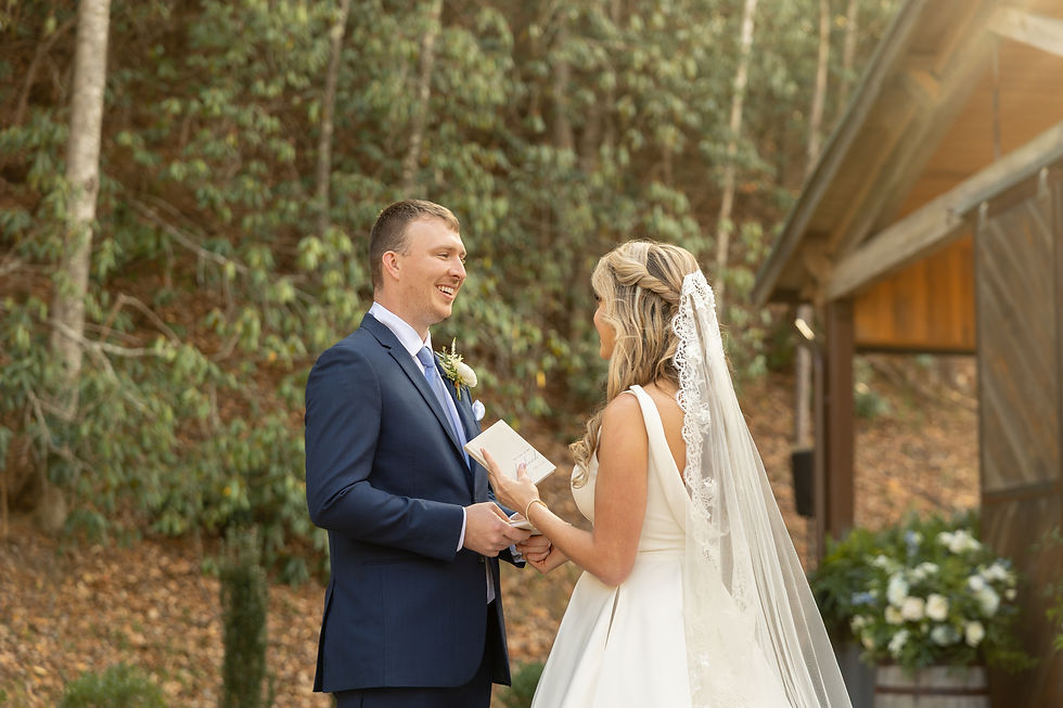 The groom laughs as the bride reads her vows.