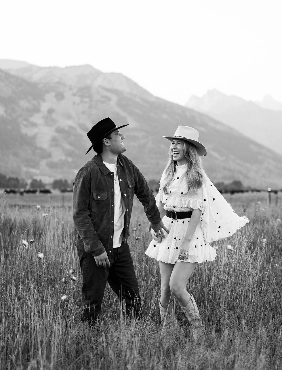 A couple laughing while holding hands in front of the mountains.