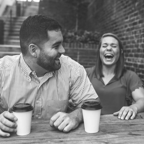 couple cracking up together as they enjoy coffees