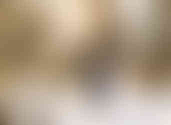 A bride and groom walk down a snow covered path in front of the trees. They are holding hands and smiling as the sun shines through.