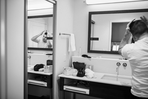 reflection of groom doing his hair 