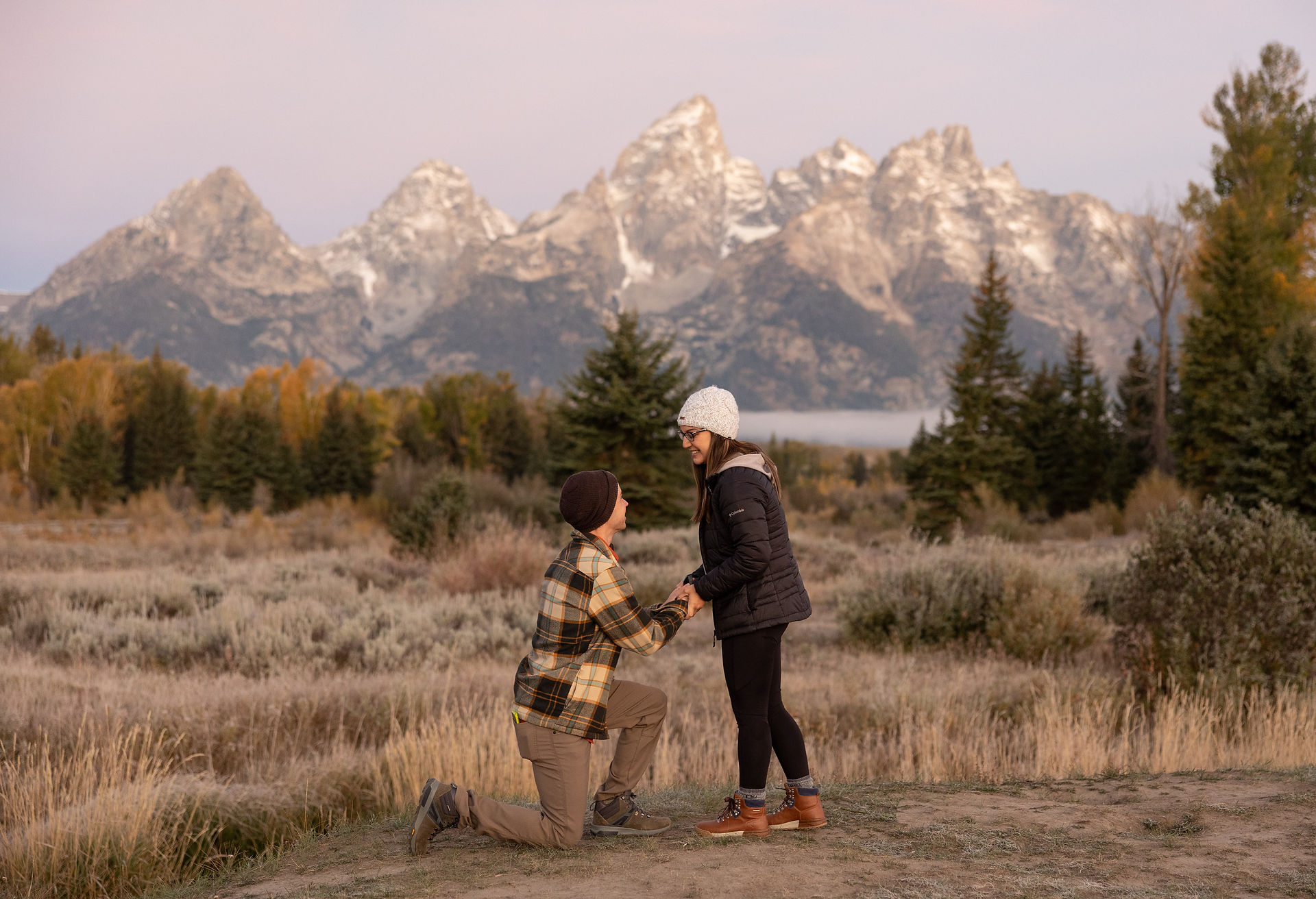 a man proposing to his girlfriend in front of the grand tetons 