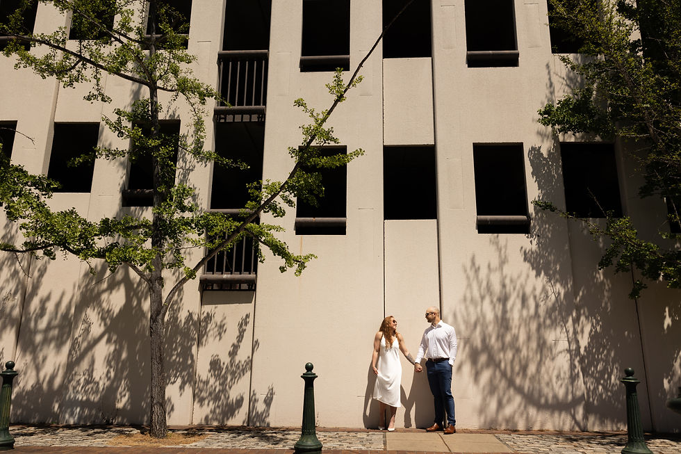 A couple smiling at each other as they stand in the sun.