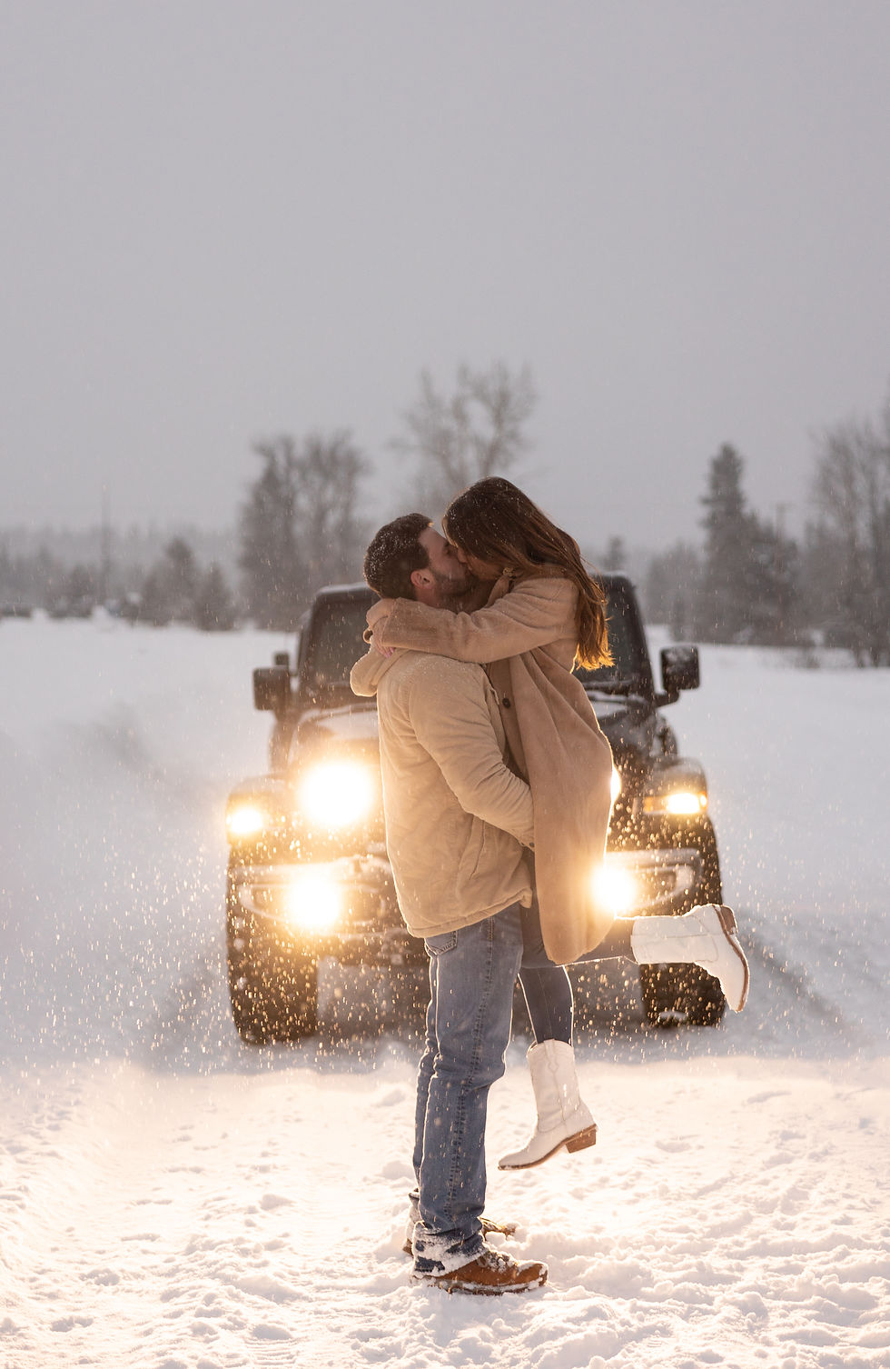 a couple kissing in the headlights of their jeep