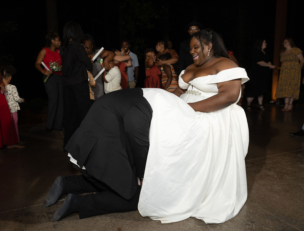 The groom retrieves the garter off of the bride by crawling underneath her dress.