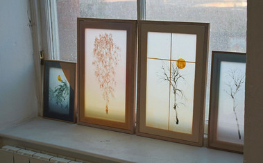 Paintings of trees on a windowsil. Paintings look like beautiful stained glass.