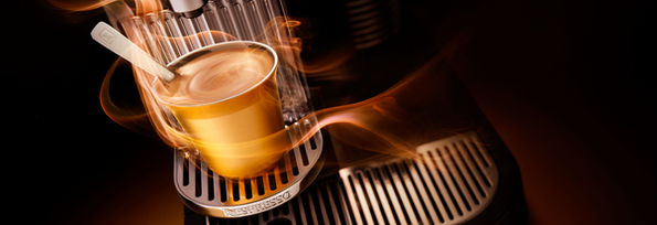 Koffie met stoom gefotografeerd met de koffiemachine in sfeervol licht. 