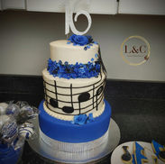 Tiered buttercream and fondant graduation cake with music notes and blue flowers along with coordinating flood-iced butter sugar cookies and cake pops.