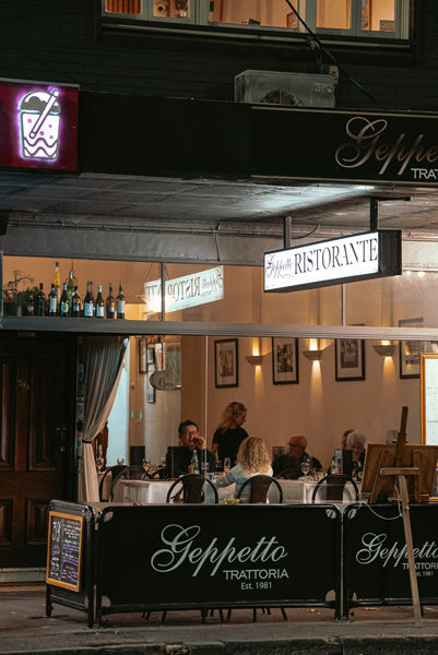 Italian restaurant in East Melbourne with guests dining outdoors near the MCG at night