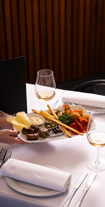 Italian antipasto platter in Melbourne with seafood, olives, cured meats and wine at a restaurant table