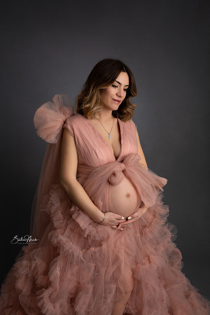future maman pensive avec robe de grossesse rose