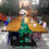 Miniatura: Mesa de madeira com resina cor verde central, cadeiras coloridas ao redor, pé de ferro preto, arranjo de flores central