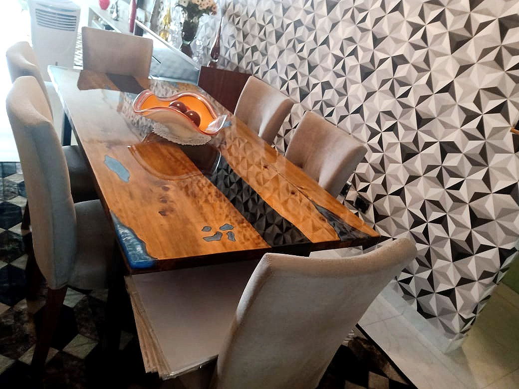 mesa de madeira com resina preta no centro, cadeiras ao redor da mesa