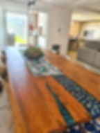 Mesa Resinada azul e conchinhas da praia, vaso decorativo sobre a mesa, janela ao fundo.