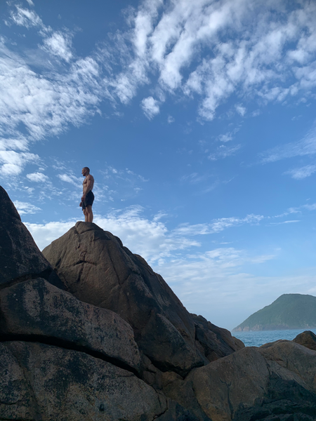 man standing on a cliff and looking at the sea