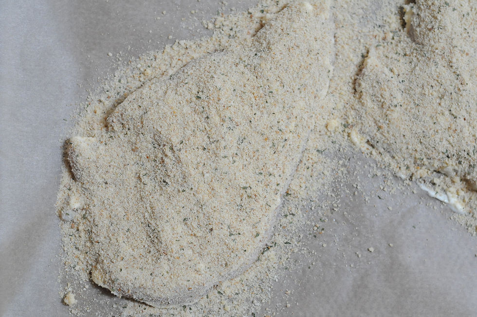 Instructional picture showing how to properly spread Italian bread crumbs on a mayo coated chicken breast for a lazy chicken parm recipe