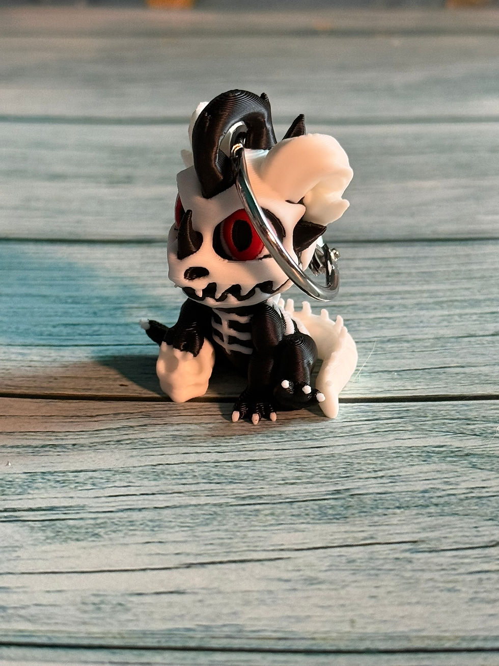 Thumbnail: Mini black and white skeleton baby dragon keychain with red eyes, skeletal details, and attached silver keyring