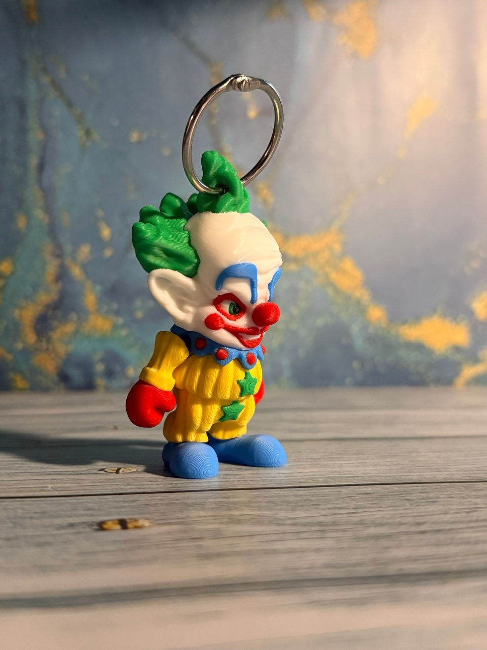 3D printed evil clown keychain with green hair, red nose, and yellow outfit attached to a metal keyring