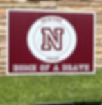 Eye-level view of a Newton Pride lawn sign in a front yard