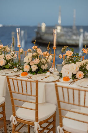 Waterfront wedding reception table with peach and ivory rose centerpieces. Chicago suburbs wedding florist.